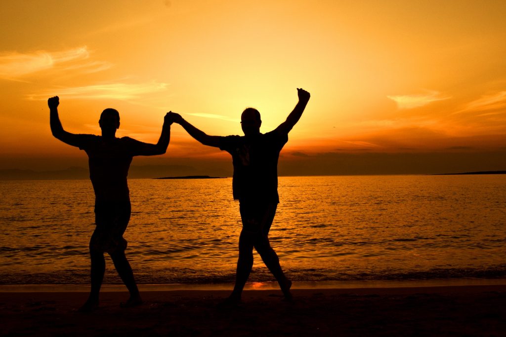 Silhouette Men on Beach Holding Hands Sunset